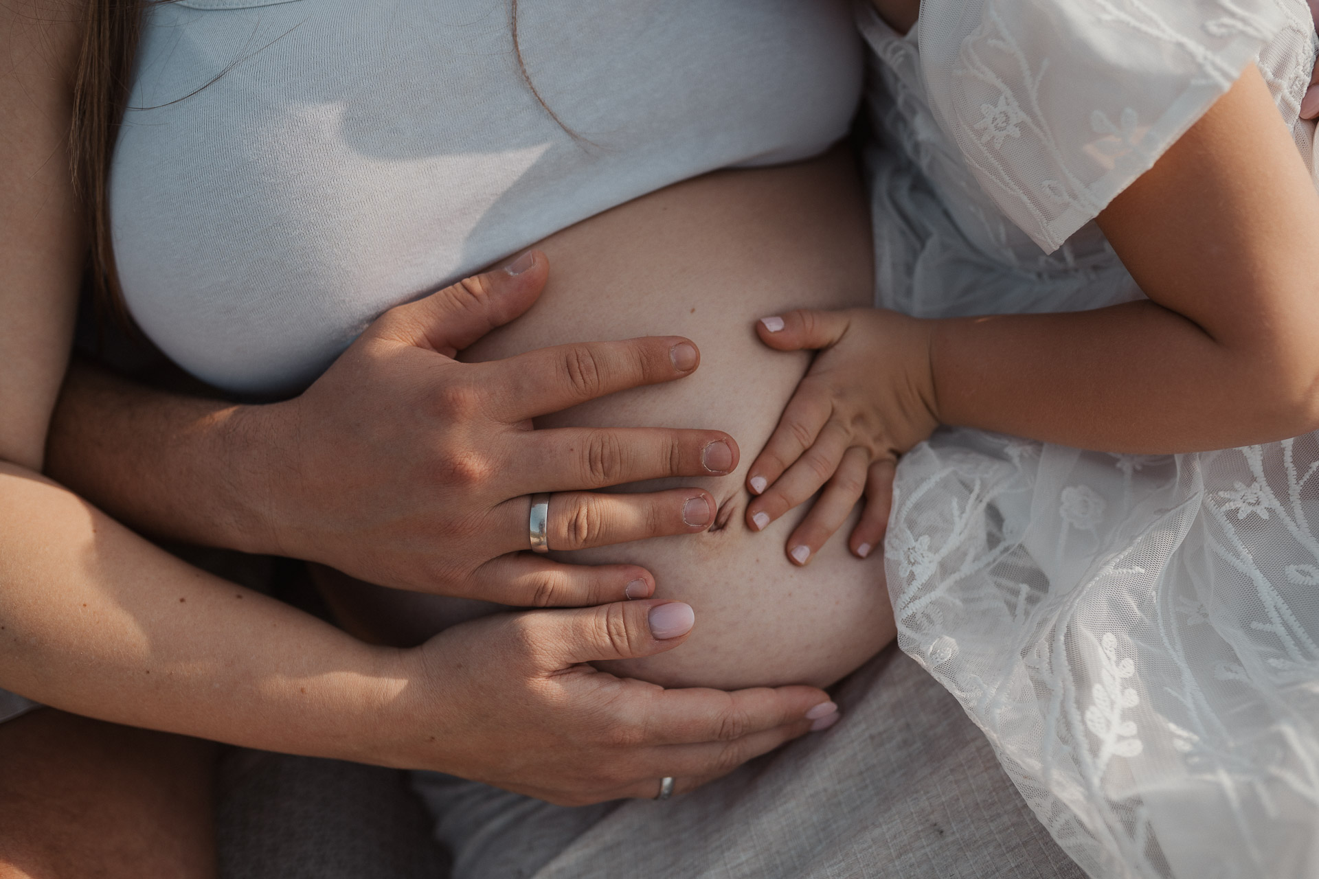 Hände der werdenden Eltern liegen auf dem Babybauch